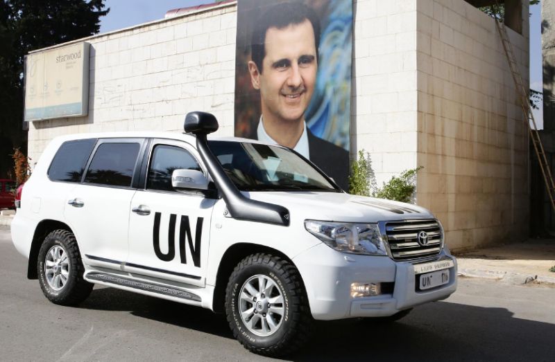A poster of Syrian President Bashar al-Assad behind the vehicle of UN special envoy for Syria